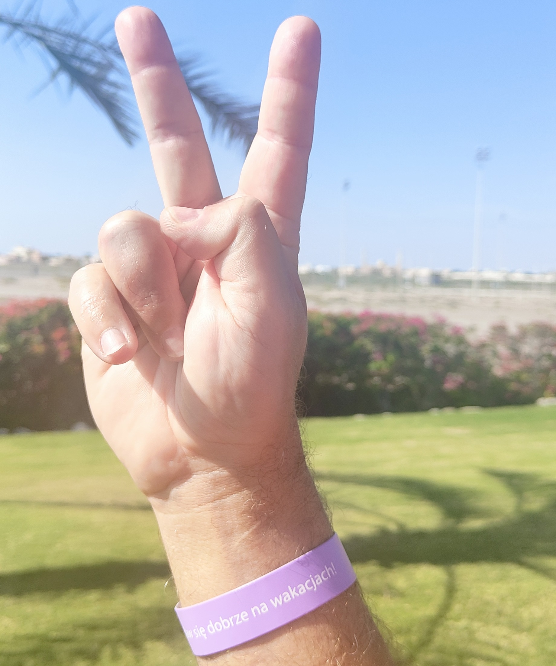 Gest zajączka wykonany na tle palm i zieleni. Baw się dobrze na wakacjach